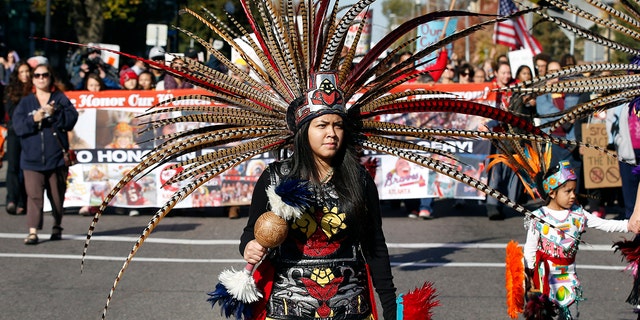 FILE - A woman wearing Native American clothing attends a "No Honor in Racism Rally" march in front of TCF Bank Stadium before an NFL football game between the Minnesota Vikings and the Kansas City Chiefs, Oct. 18, 2015, in Minneapolis.