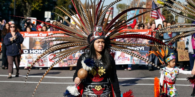 A woman wearing Native American clothing attends a "No Honor in Racism Rally" march in front of TCF Bank Stadium before an NFL football game between the Minnesota Vikings and the Kansas City Chiefs, Oct. 18, 2015, in Minneapolis. 