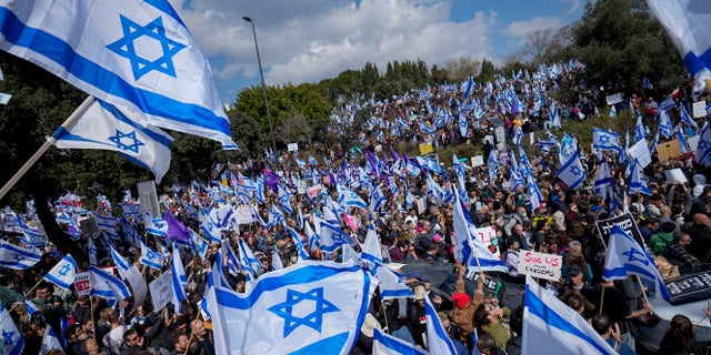 Israelis wave national flags during protest against plans by Prime Minister Benjamin Netanyahu's new government to overhaul the judicial system, outside the Knesset, Israel's parliament, in Jerusalem, Monday, Feb. 13, 2023. Thousands of Israelis protested outside the country's parliament on Monday ahead of a preliminary vote on a bill that would give politicians greater power over appointing judges, part of a judicial overhaul proposed by Prime Minister Benjamin Netanyahu's government.