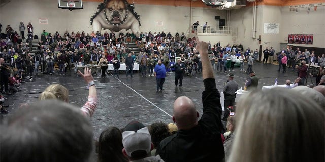 Seorang pria mengangkat tangannya dengan pertanyaan untuk Palestina Timur, Walikota Ohio Trent Conaway, tengah, saat rapat balai kota di SMA East Palestine di East Palestine, Ohio, Rabu, 15 Februari 2023. Pertemuan itu diadakan untuk menjawab pertanyaan tentang pembersihan berkelanjutan dari penggelinciran pada 3 Februari, dari kereta barang Norfolk Southern yang membawa bahan berbahaya.