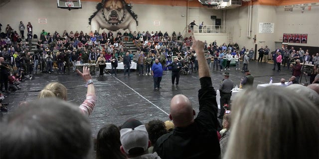 A man raises his hand with a question for East Palestine, Ohio Mayor Trent Conaway, center, during a town hall meeting at East Palestine High School in East Palestine, Ohio, Wednesday, Feb. 15, 2023. The meeting was held to answer questions about the ongoing cleanup from the derailment on Feb, 3, of a Norfolk Southern freight train carrying hazardous material. 