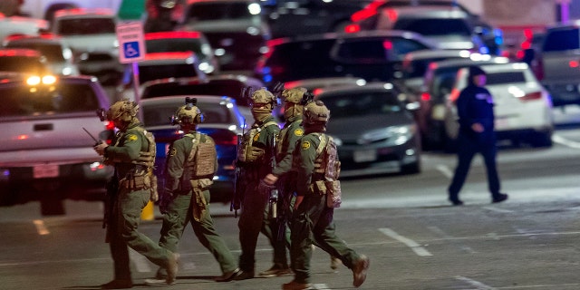 Law enforcement agents walk in the parking lot of a shopping mall, Wednesday, Feb. 15, 2023, in El Paso, Texas.