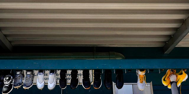 An attendant lowers Pittsburgh Pirates shoes for cleaning during spring training Saturday, February 18, 2023, in Bradenton, Florida.