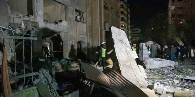 Sur cette photo publiée par l'agence de presse officielle syrienne SANA, les gens voient les dégâts dans un quartier résidentiel après une frappe aérienne israélienne tôt le matin dans la capitale Damas, en Syrie, le dimanche 19 février 2023. (SANA via AP)