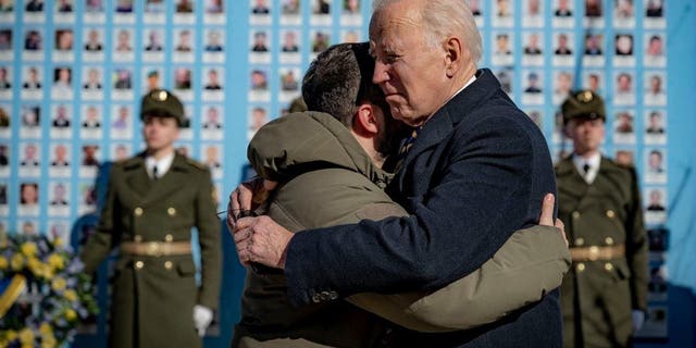 President Biden, right, and Ukrainian President Volodymyr Zelenskyy hug as they say goodbye at the Memorial Wall of Fallen Defenders of Ukraine in Russian-Ukrainian War with photos of killed soldiers, in Kyiv, Ukraine, Monday, Feb. 20, 2023.