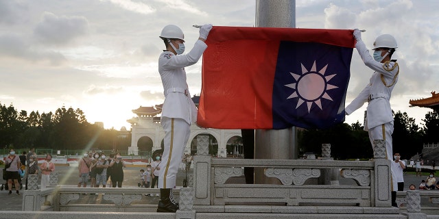 FILE - Two soldiers fold the national flag during the daily flag ceremony in Liberty Square of Chiang Kai-shek Memorial Hall in Taipei, Taiwan, Saturday, July 30, 2022.