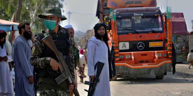 Pakistani paramilitary, frontline and Taliban fighters guard their sides of the Afghan-Pakistan border as a truck moves towards a checkpoint in Torkham, Khyber Agency, Pakistan.