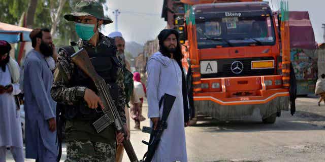 Pakistani paramilitary, frontline and Taliban fighters guard their sides of the Afghan-Pakistan border as a truck moves towards a checkpoint in Torkham, Khyber Agency, Pakistan.