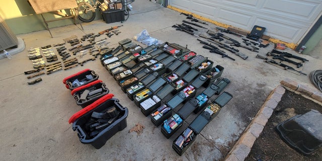 Nearly two dozen guns and thousands of rounds of ammunition are displayed following an arrest on Jan. 25, 2023, in Azusa, California. The guns were seized from the home of a man who had mental health problems.