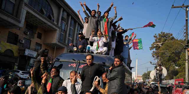 Supporters of Pakistan's former Prime Minister Imran Khan climb on a police van during a rally, in Lahore, Pakistan, on Feb. 22, 2023. Former Army Gen. Amjad Shoaib was arrested for inciting the public against national institutions.