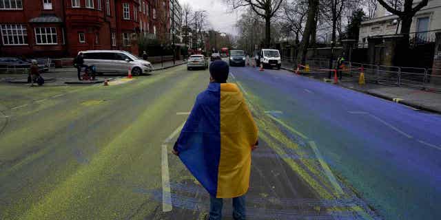 La policía del Reino Unido arrestó a 4 manifestantes después de pintar una bandera ucraniana gigante frente a la embajada rusa en Londres. 4 Un manifestante lleva una bandera ucraniana después de que un grupo pinta una bandera ucraniana gigante frente a la embajada rusa en Londres el 23 de febrero de 2023.