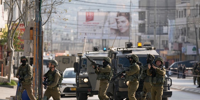 Israeli soldiers take up positions at the scene of a Palestinian shooting attack at the Hawara checkpoint, near the West Bank city of Nablus, Sunday, Feb. 26, 2023. 
