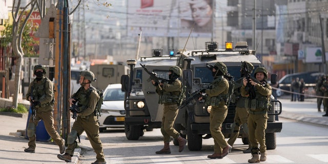 Israeli soldiers take up positions at the scene of a Palestinian shooting attack at the Hawara checkpoint, near the West Bank city of Nablus, Sunday, Feb. 26, 2023.