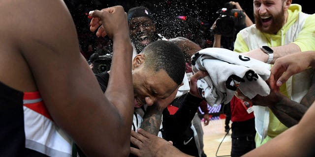 Portland Trail Blazers guard Damian Lillard, center, is doused by teammates after setting franchise and career highs with 71 points during an NBA basketball game against the Houston Rockets in Portland, Oregon, Sunday, Feb. 26, 2023. 