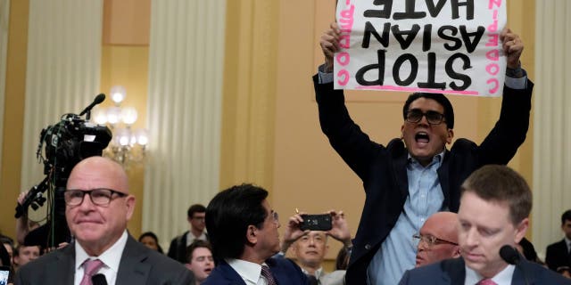 A protester interrupts H.R. McMaster, former national security adviser to former President Trump, as testifies during a hearing of a special House committee dedicated to countering China, on Capitol Hill, Tuesday, Feb. 28, 2023, in Washington. At right is Matthew Pottinger, former deputy national security adviser to former President Trump.