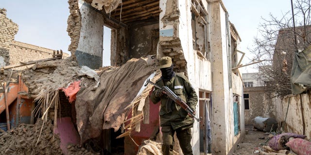 A Taliban fighter checks an Islamic State group house that was destroyed in the ongoing conflict between the two in Kabul, Afghanistan, on Feb. 14, 2023.