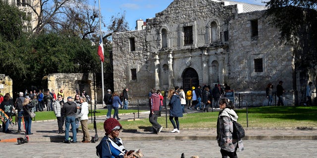 A tourist uses her phone and relaxes with her dogs in front of Mission San Antonio de Valero, better known as the Alamo, on Dec. 9, 2018. The former Franciscan mission was the site of the Battle of the Alamo in 1836 during Texas' war for independence from Mexico; Texan defenders were defeated by Mexican troops under General Antonio Lopez de Santa Anna.