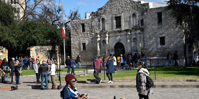 A tourist uses her phone and relaxes with her dogs in front of Mission San Antonio de Valero, better known as the Alamo, on Dec. 9, 2018. The former Franciscan mission was the site of the Battle of the Alamo in 1836 during Texas' war for independence from Mexico; Texan defenders were defeated by Mexican troops under General Antonio Lopez de Santa Anna. 