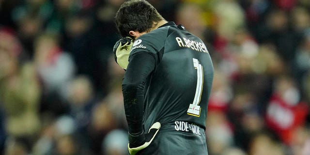 El portero del Liverpool, Alisson, hace un gesto después de que Vinicius Junior del Real Madrid anotó el segundo gol de su equipo durante el partido de ida de los octavos de final de la Liga de Campeones de la UEFA entre el Liverpool y el Real Madrid en el estadio Anfield de Liverpool, Inglaterra, el martes 21 de febrero de 2023.