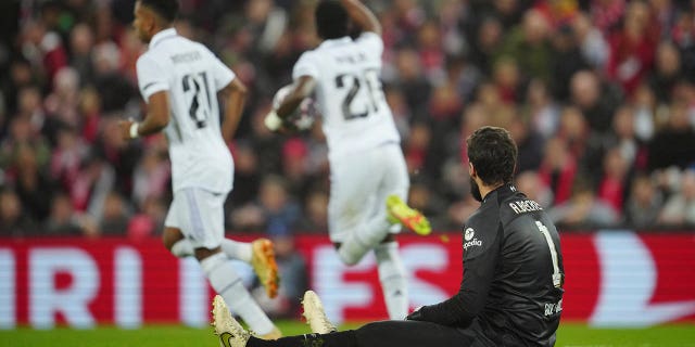 El portero del Liverpool, Alisson, abajo, hace un gesto mientras Vinicius Junior del Real Madrid celebra después de marcar el primer gol de su equipo durante la Liga de Campeones, octavos de final, partido de ida de fútbol entre el Liverpool y el Real Madrid en el estadio Anfield de Liverpool, Inglaterra, el martes 2 de febrero. 2020. 21, 2023.