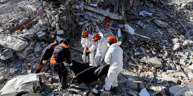 Rescuers carry the body of a victim taken out of the rubble in the aftermath of the deadly earthquake in Antakya, Turkey, on Feb. 17, 2023.
