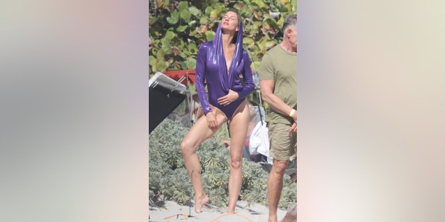 Gisele in a shimmery purple swimsuit.