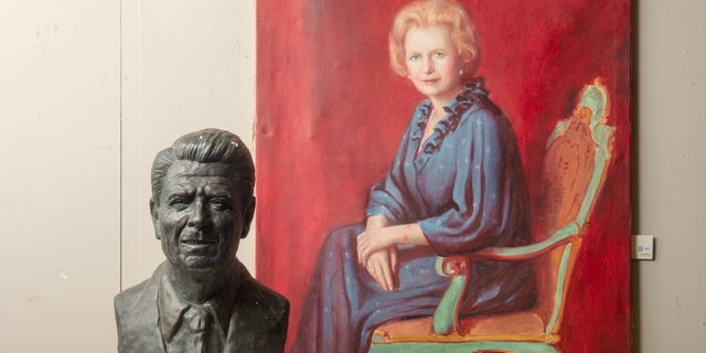 A large bronze plaster bust of President Ronald Reagan and an oil painting of Margaret Thatcher seated in a blue dress in a green armchair.