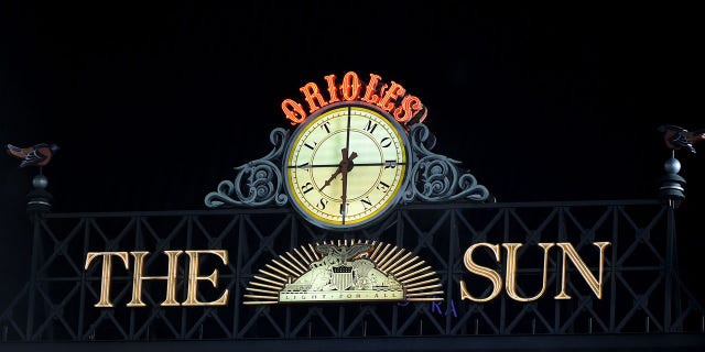 The Sun logo and the Baltimore Orioles clock are shown above the Camden Yards scoreboard Sept. 30, 2021.