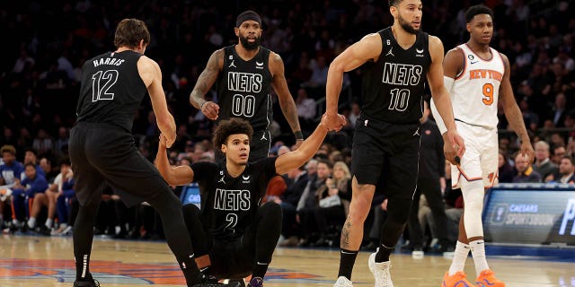 February 13, 2023; New York, New York, United States; Brooklyn Nets forward Joe Harris (12) and guard Ben Simmons (10) help Cameron Johnson (2) up after a foul by New York Knicks guard RJ Barrett (9) in the second quarter at Madison Square Garden.