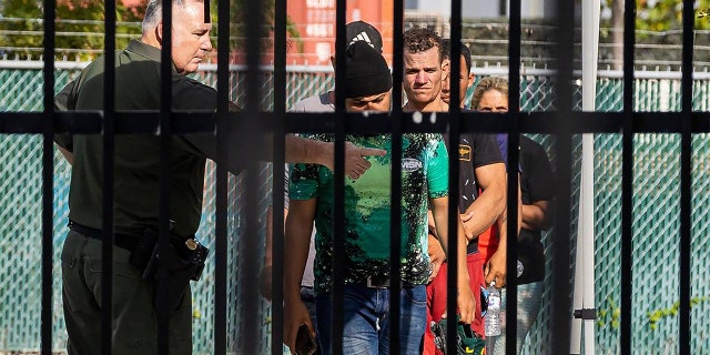 A U.S. Border Patrol agent directs a group of Cuban migrants at the U.S. Customs and Border Protection station in Marathon, Florida, on Sunday, Jan. 8, 2023.