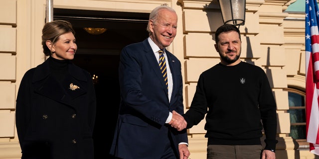 President Biden, center, shakes hands with Ukrainian President Volodymyr Zelenskyy, right, as they pose with Olena Zelenska, left, spouse of President Zelenskyy, at Mariinsky Palace during an unannounced visit in Kyiv, Ukraine, Monday, Feb. 20, 2023. 