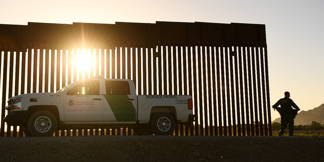 A Border Patrol agent walks between a gap along the border wall between the U.S. and Mexico in Yuma, Arizona, on June 1, 2022.