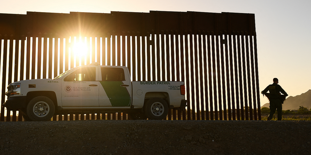 A Border Patrol agent walks between a gap along the border wall between the U.S. and Mexico in Yuma, Arizona, on June 1, 2022.