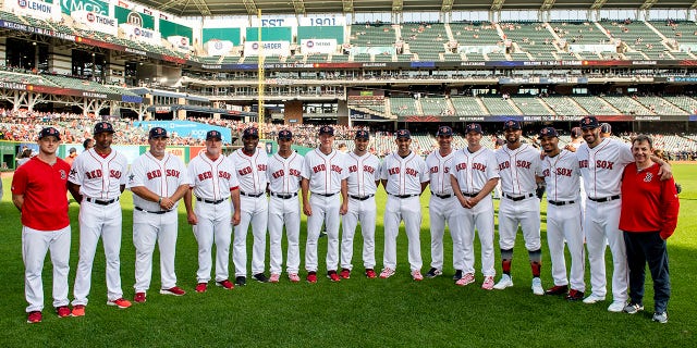 Video coordinator J.T. Watkins, first base coach Tom Goodwin, bullpen coach Craig Bjornson, pitching coach Dana LeVangie, third base coach Carlos Febles, bullpen catcher Mani Martinez, bench coach Ron Roenicke, coach Ramon Vazquez, manager Alex Cora, assistant hitting coach Andy Barkett, hitting coach Tim Hyers, Xander Bogaerts (2) Mookie Betts (50), J.D. Martinez (28) and video coordinator Billy Broadbent of the Boston Red Sox pose for a group photograph before the 2019 MLB All-Star Game at Progressive Field July 9, 2019, in Cleveland.