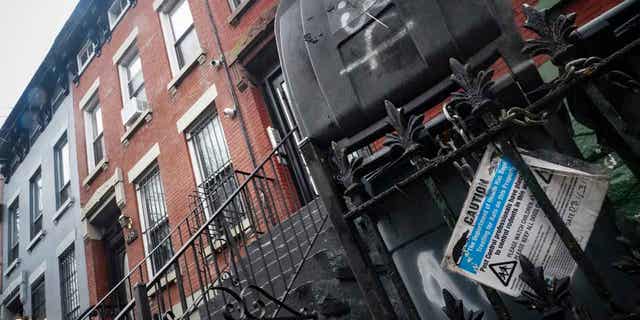 A caution sign for rodenticide is posted on a fence next door to a building owned by New York City Mayor Eric Adams in Brooklyn, New York, on Dec. 7, 2022. 