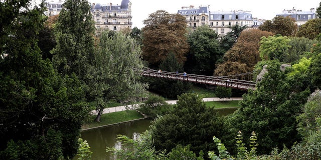 Las autoridades francesas encuentran la cabeza de una mujer decapitada y otras partes del cuerpo en un parque público: informes 4 Archivo: La gente camina sobre un puente colgante diseñado por el ingeniero francés Gustave Eiffel en el parque Bautes-Chaumont de París.