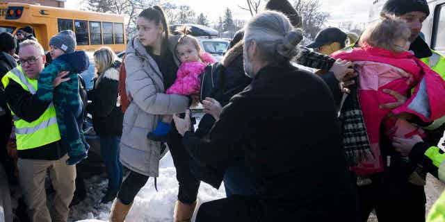 Parents and their children are loaded onto a warming bus after a city bus crashed into a daycare center in Laval, Quebec, on Feb. 8, 2023.