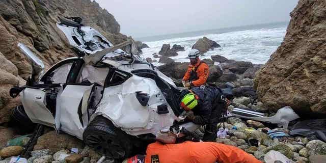 Emergency personnel respond to a Tesla over the side of Highway 1 on Jan. 1, 2023