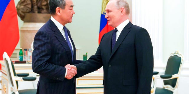 Russian President Vladimir Putin, right, greets Chinese Communist Party's foreign policy chief Wang Yi during their meeting at the Kremlin in Moscow on Wednesday, Feb. 22, 2023.