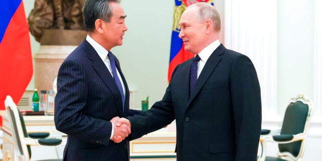 Russian President Vladimir Putin greets Chinese Communist Party's foreign policy chief Wang Yi during their meeting at the Kremlin in Moscow, Russia, Wednesday, Feb. 22, 2023.