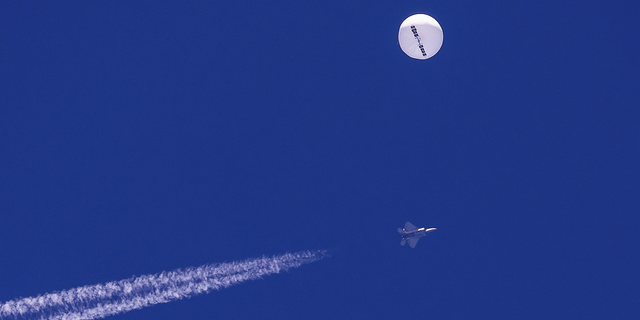 The Chinese spy balloon drifts above the Atlantic Ocean just off the coast of South Carolina with a fighter jet and its contrail seen below it on Saturday, Feb. 4.