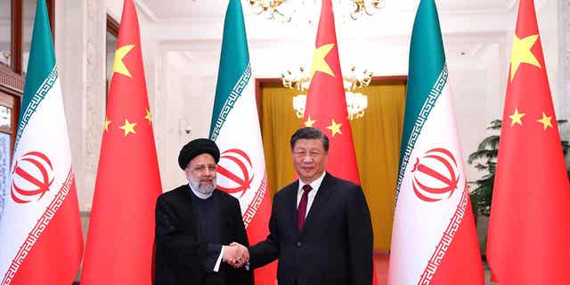 In this photo released by the official website of the office of the Iranian Presidency, President Ebrahim Raisi, left, shakes hands with his Chinese counterpart Xi Jinping in an official welcoming ceremony in Beijing, Tuesday, Feb. 14, 2023.