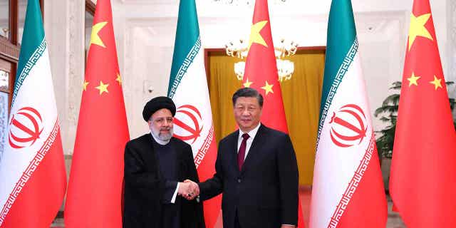 In this photo released by the official website of the office of the Iranian Presidency, President Ebrahim Raisi, left, shakes hands with his Chinese counterpart Xi Jinping in an official welcoming ceremony in Beijing, Tuesday, Feb. 14, 2023.