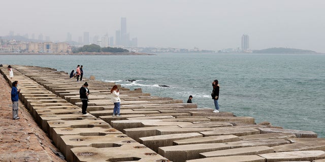 China reclama un "objeto no identificado" en su espacio aéreo, que está dispuesto a derribar 4 Un visitante posa para fotos en la costa de Qingdao, provincia de Shandong, China, 29 de abril de 2021.