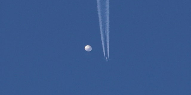 In this photo provided by Brian Branch, a large balloon drifts above the Kingston, North Carolina area, with an airplane and its contrail seen below it. 