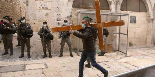 A Christian man carries a cross along the Via Dolorosa ahead of the Good Friday procession in Jerusalem's Old City, on April 2, 2021. Israeli police on Thursday, Feb. 2, 2023 arrested an American tourist after he allegedly knocked down and broke a statue of Jesus in a church in Jerusalem's Old City. Police said the man's mental health was being assessed. (AP Photo/Maya Alleruzzo)