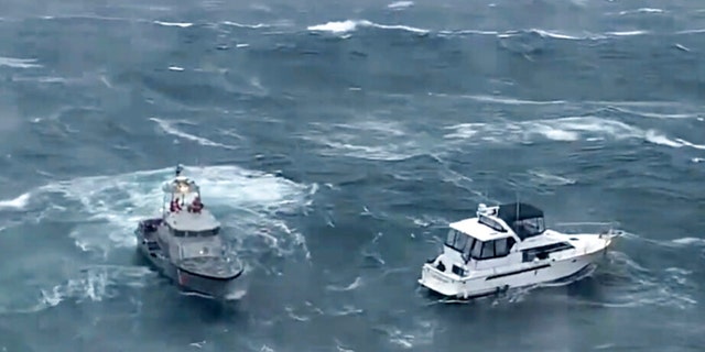 In this photo provided by the U.S. Coast Guard Pacific Northwest, a Coast Guard ship, left, attempts to a rescue a distressed yacht at the mouth of the Columbia River between Oregon and Washington state on Friday, Feb. 3, 2023. 