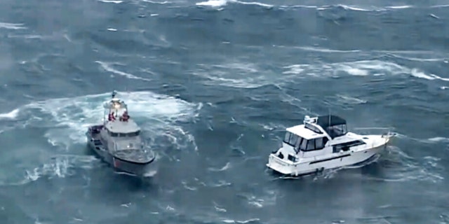 In this photo provided by the US Coast Guard Pacific Northwest, a Coast Guard ship (left) attempts to rescue a yacht in distress at the mouth of the Columbia River between Oregon and Washington on Friday, February 3, 2023. 