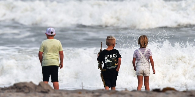 Children watch the rough surf at Cocoa Beach, Florida, as Tropical Storm Nicole approaches the east coast of Florida. 