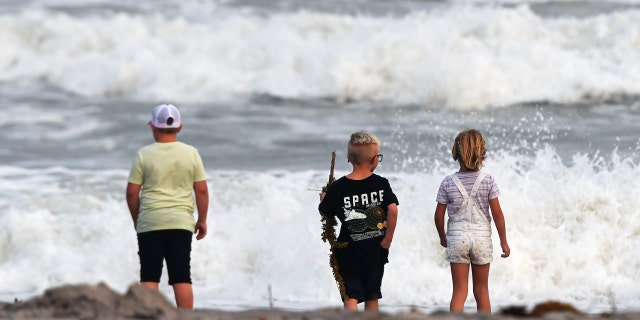Children watch the rough surf at Cocoa Beach, Florida, as Tropical Storm Nicole approaches the east coast of Florida.